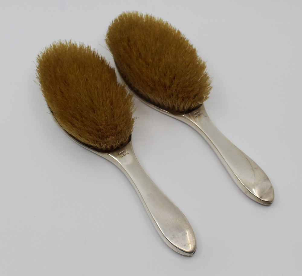 A five-piece Art Deco sterling silver and faux tortoiseshell vanity set featuring a hand mirror, two handled hairbrushes, and two clothes brushes with silver leaf-wreath inlays. View XIV