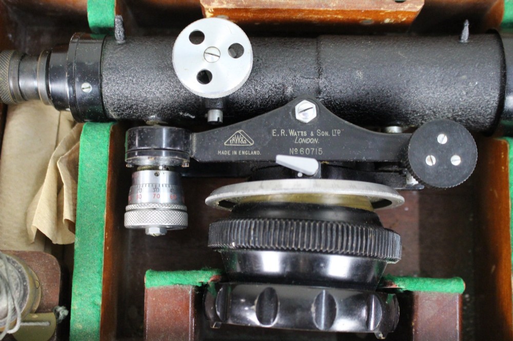 A vintage black metal surveyor level set inside its original fitted wooden transport box with a leather strap and manufacturer label. View III