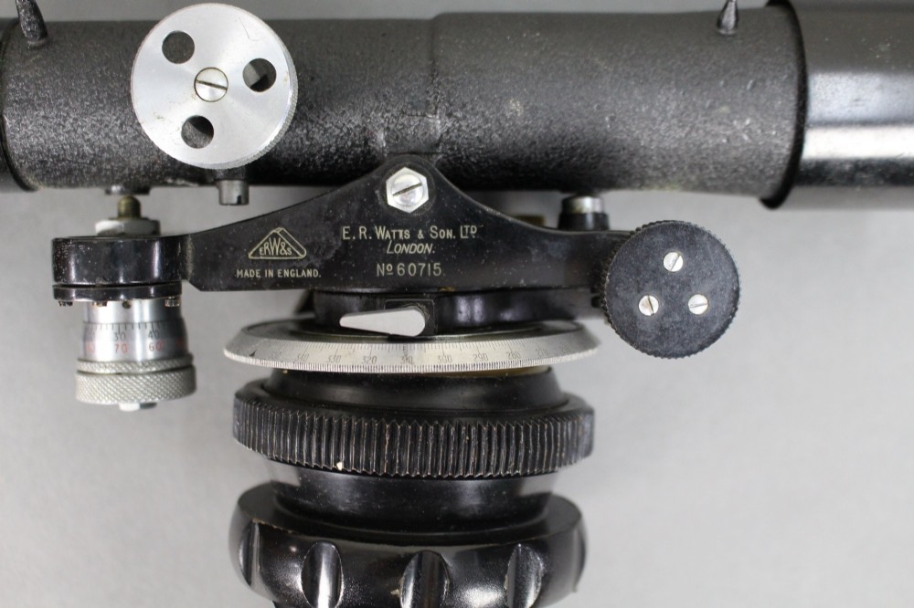 A vintage black metal surveyor level set inside its original fitted wooden transport box with a leather strap and manufacturer label. View VI