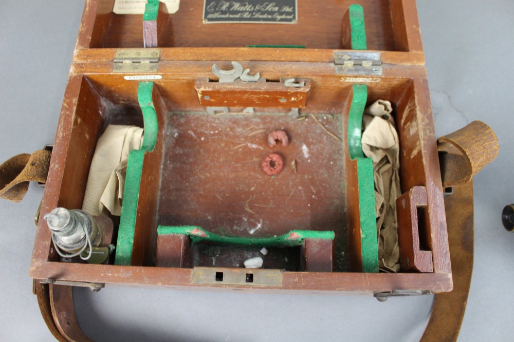 A vintage black metal surveyor level set inside its original fitted wooden transport box with a leather strap and manufacturer label. View VII