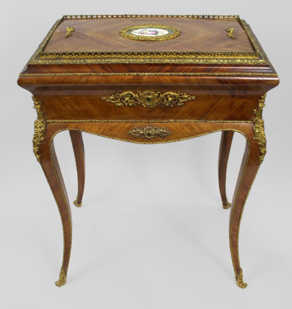 A 19th-century French kingwood jardiniere table featuring geometric parquetry inlay, ornate gilt-bronze mounts, cabriole legs, and a central floral porcelain plaque.