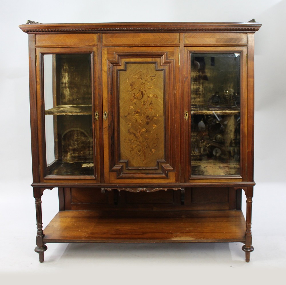 Late Victorian rosewood display cabinet featuring a central floral marquetry panel, glass side doors, brass gallery rail, and a lower shelf. View II