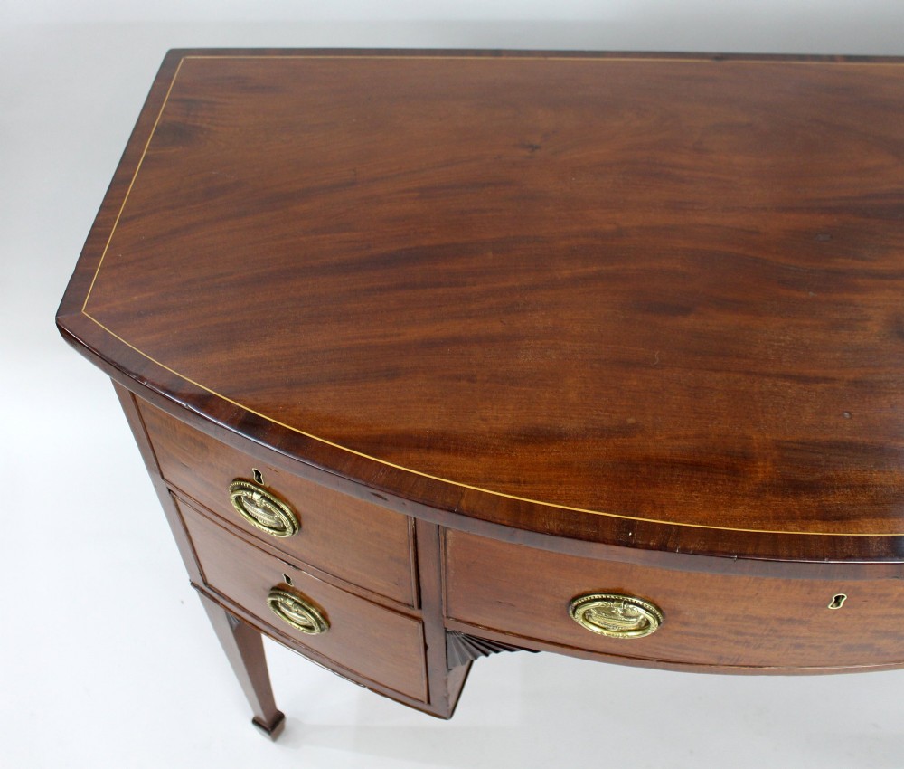 A George III bow-fronted mahogany serving table with brass oval handles, stringing inlay, and square tapered legs. View IV
