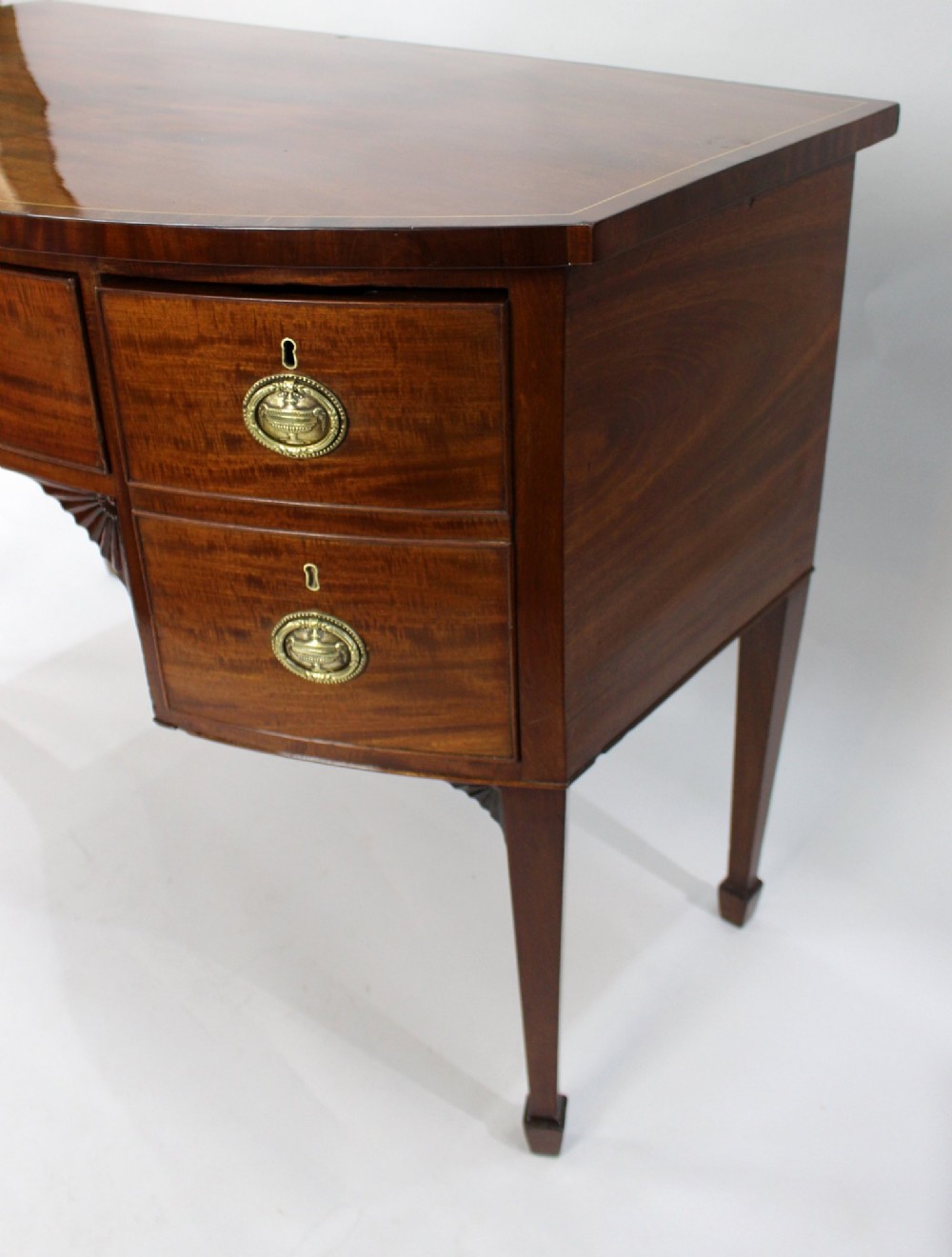 A George III bow-fronted mahogany serving table with brass oval handles, stringing inlay, and square tapered legs. View VII