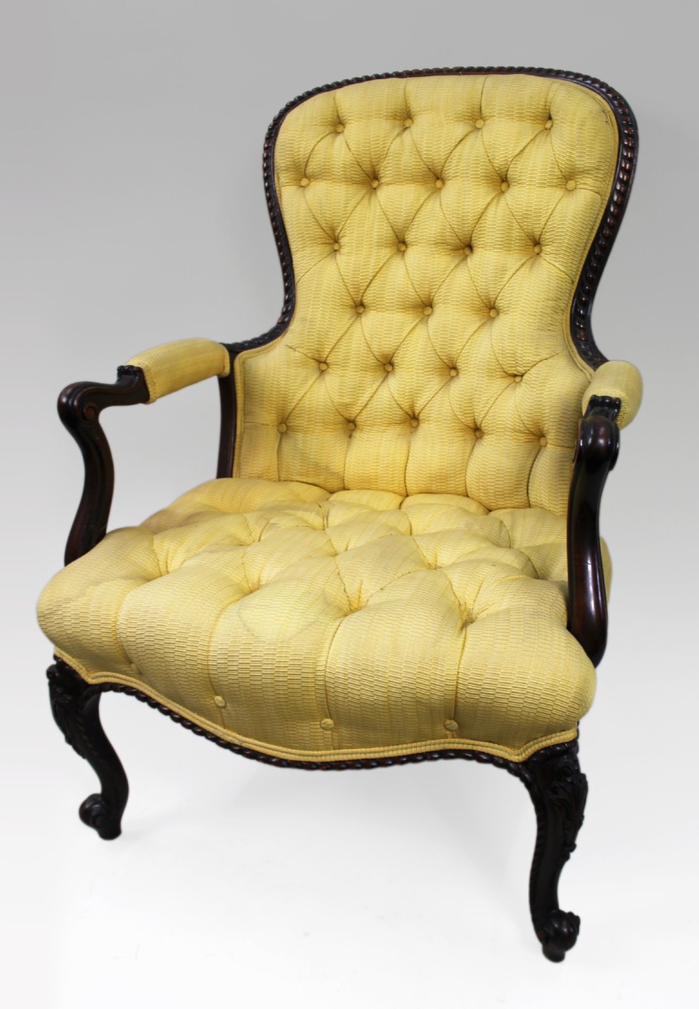 A Victorian mahogany button-back armchair with yellow tufted fabric upholstery, padded armrests, and carved cabriole front legs. View II