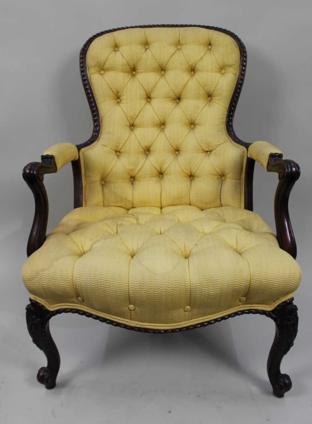 A Victorian mahogany button-back armchair with yellow tufted fabric upholstery, padded armrests, and carved cabriole front legs. View III