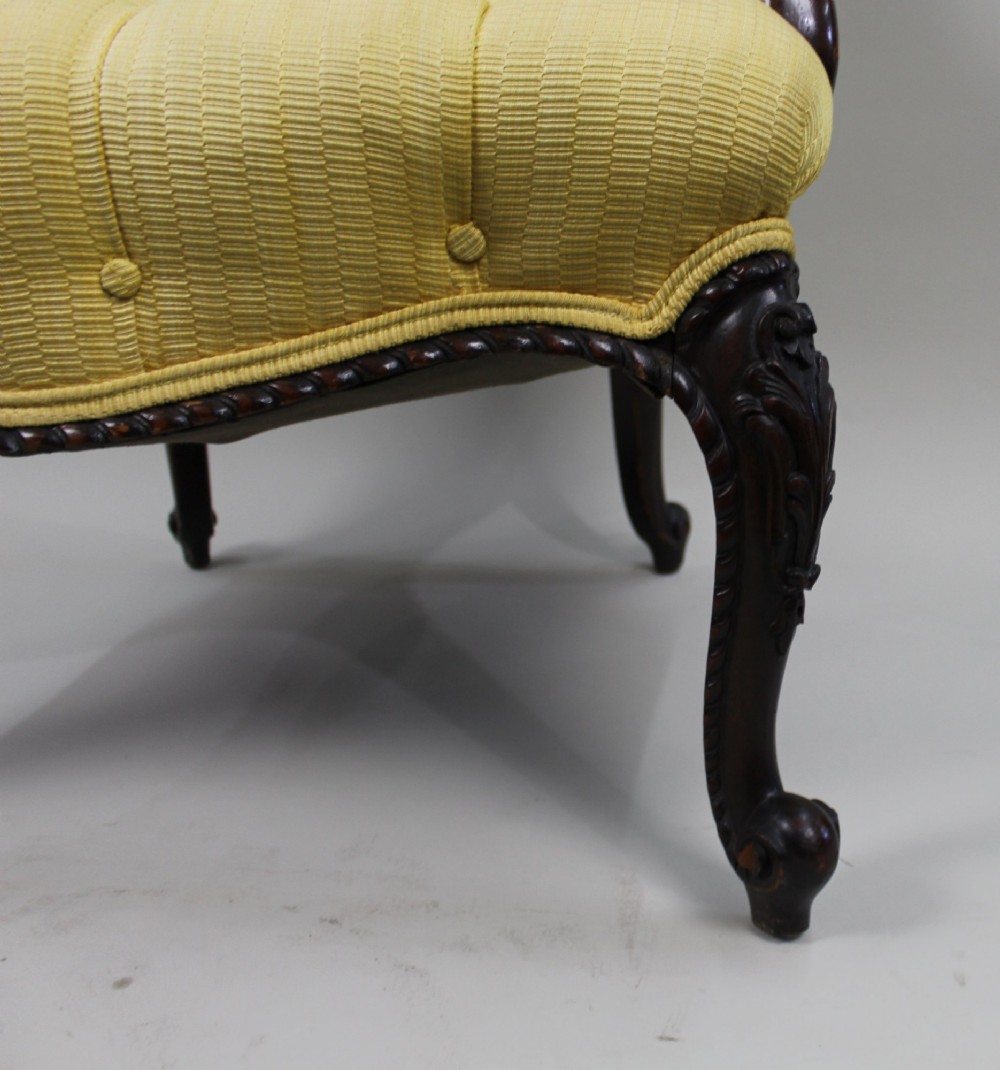 A Victorian mahogany button-back armchair with yellow tufted fabric upholstery, padded armrests, and carved cabriole front legs. View V