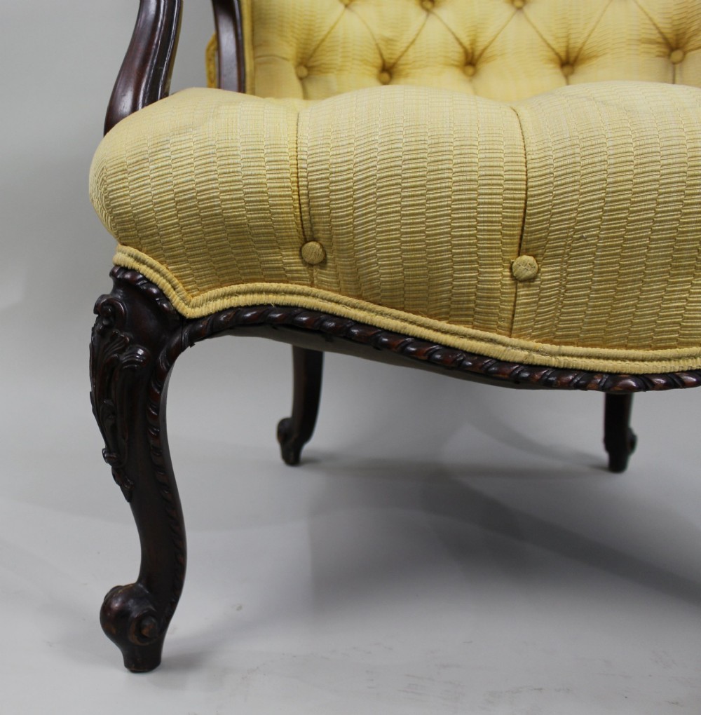 A Victorian mahogany button-back armchair with yellow tufted fabric upholstery, padded armrests, and carved cabriole front legs. View VI