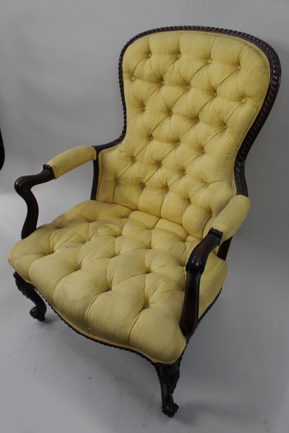 A Victorian mahogany button-back armchair with yellow tufted fabric upholstery, padded armrests, and carved cabriole front legs. View VIII