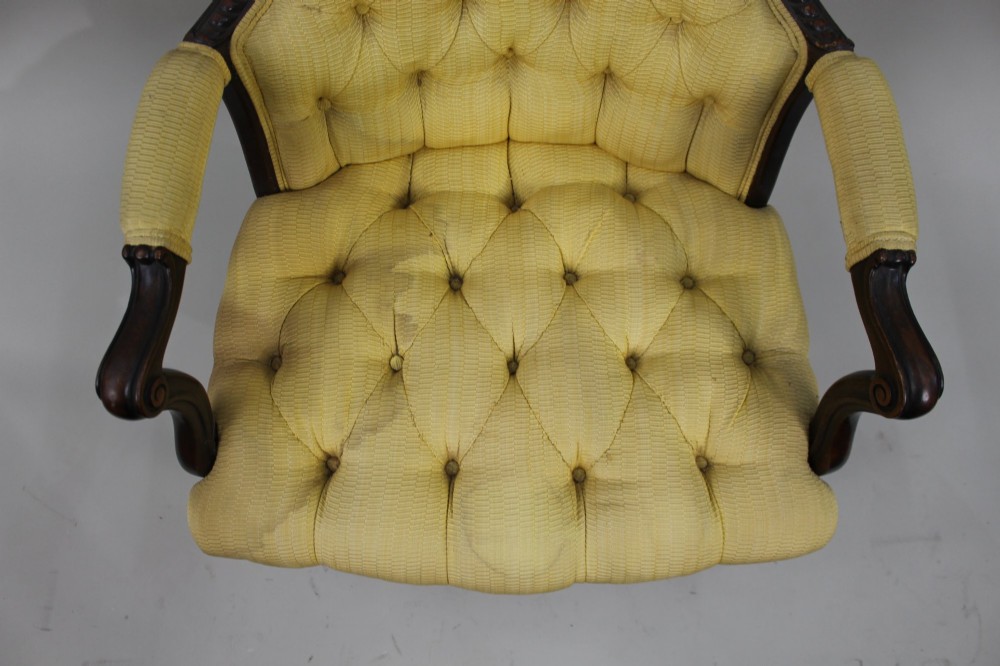 A Victorian mahogany button-back armchair with yellow tufted fabric upholstery, padded armrests, and carved cabriole front legs. View IX