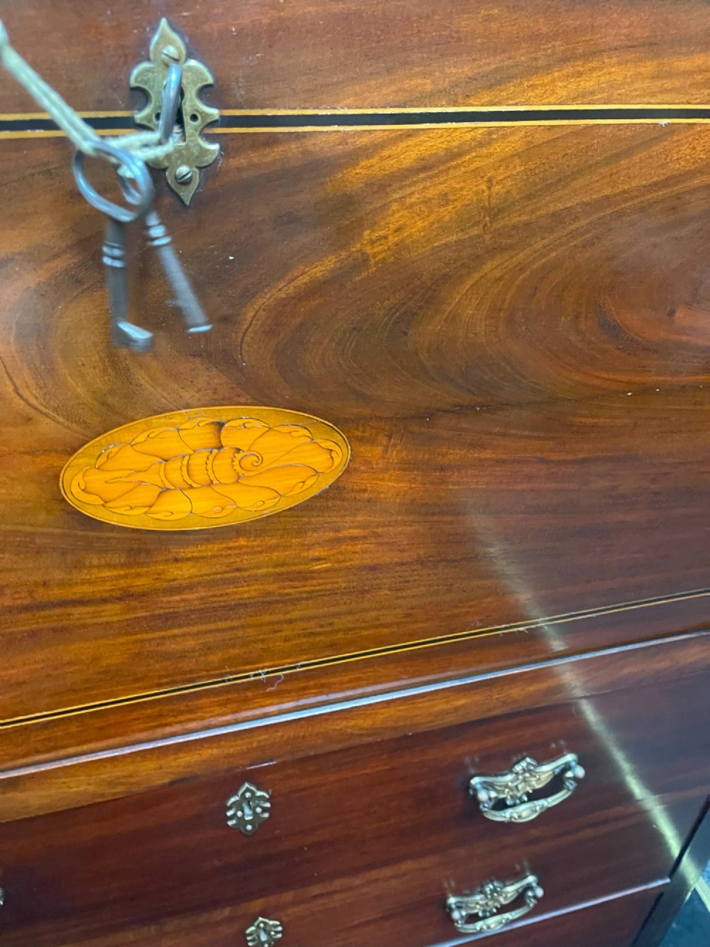 A tall Georgian mahogany secretaire chest featuring stepped upper cabinets with oval satinwood inlay, a pull-out writing drawer, and three lower drawers with brass handles. View XI
