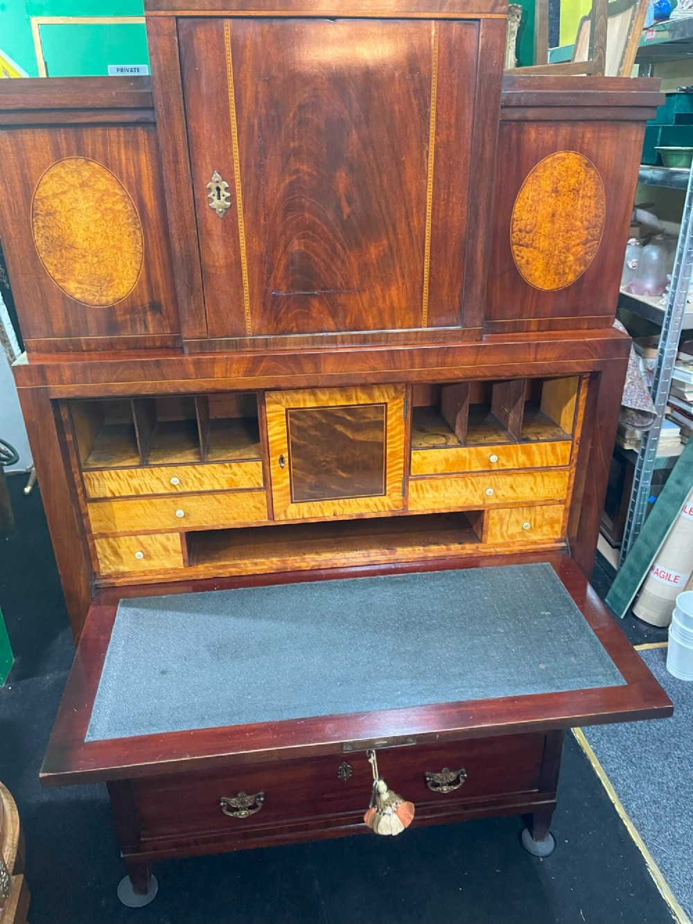 A tall Georgian mahogany secretaire chest featuring stepped upper cabinets with oval satinwood inlay, a pull-out writing drawer, and three lower drawers with brass handles. View XIII
