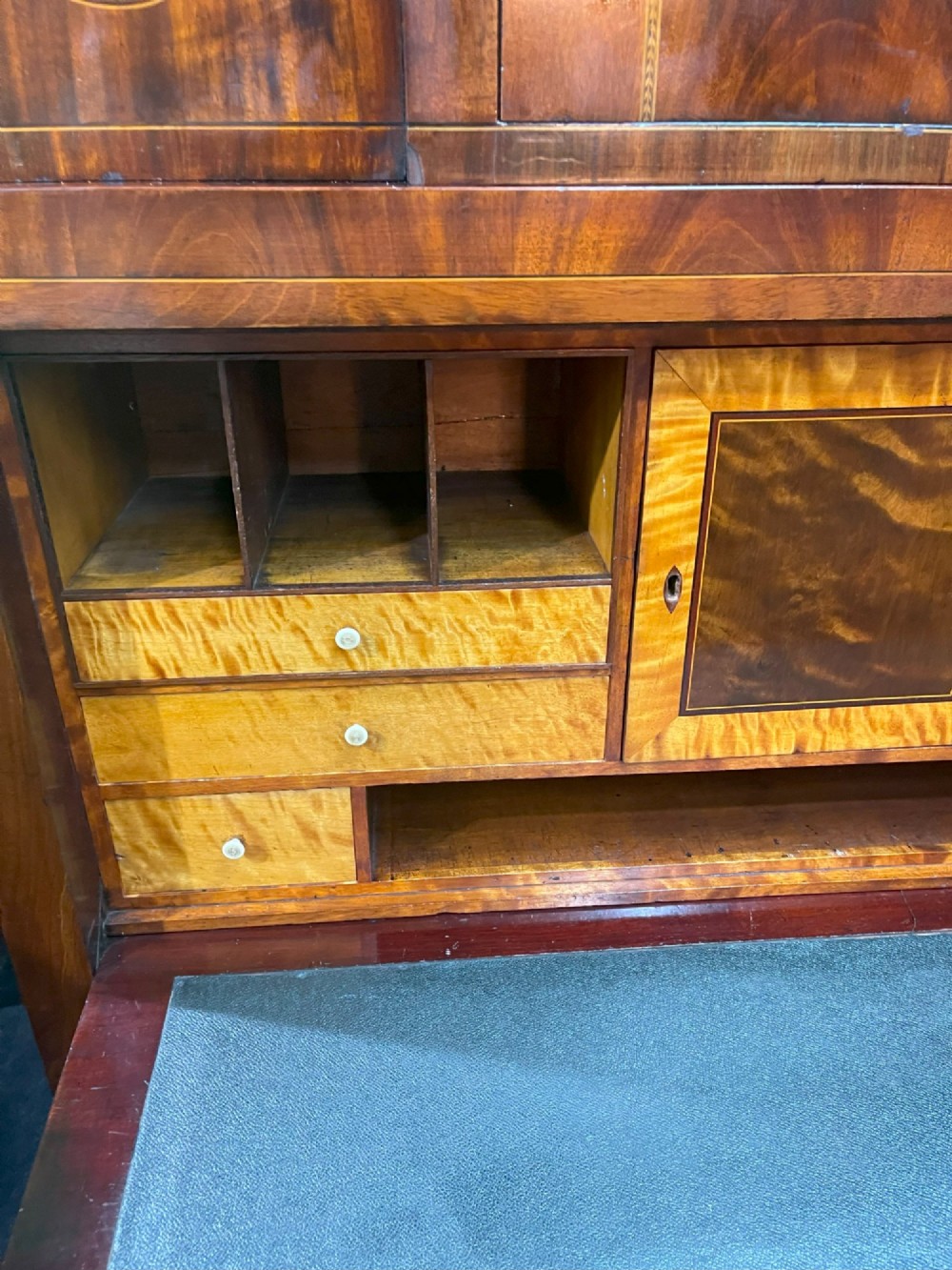 A tall Georgian mahogany secretaire chest featuring stepped upper cabinets with oval satinwood inlay, a pull-out writing drawer, and three lower drawers with brass handles. View XIV