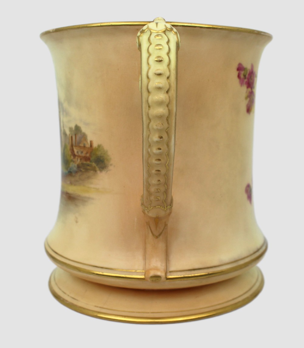 An Edwardian Royal Worcester porcelain loving cup featuring twin gilded scroll handles, a cream blush ground, hand-painted floral motifs, and a central gilt monogram. View XIII