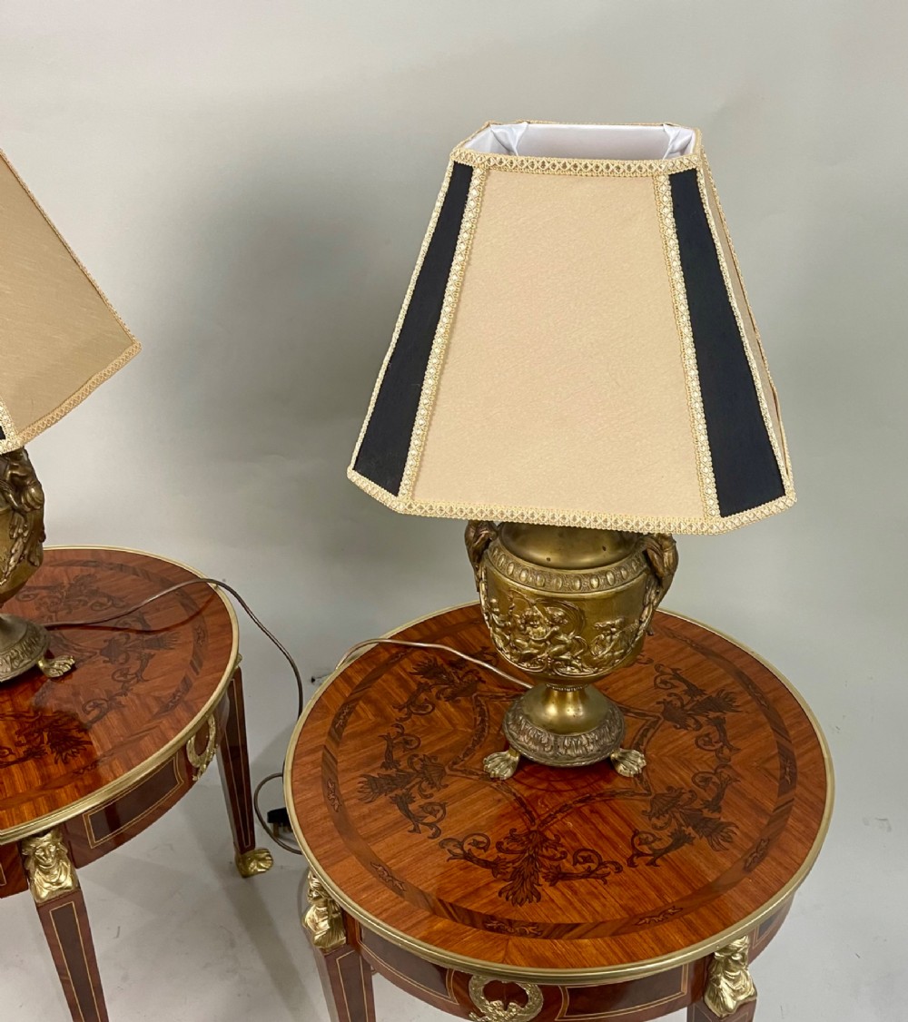 A pair of antique French gilt bronze urn-form table lamps decorated with putti reliefs and fitted with neutral fabric shades. View III