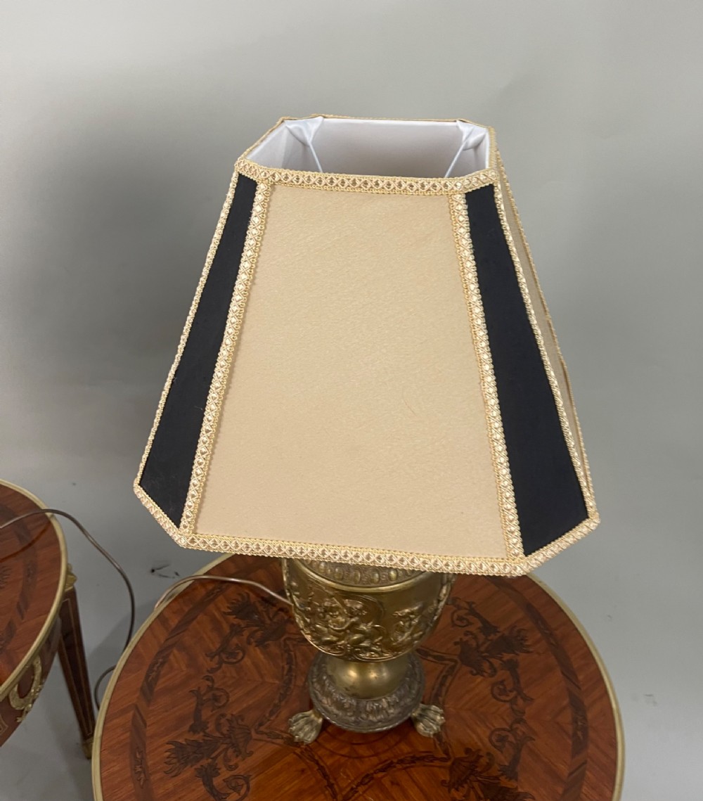 A pair of antique French gilt bronze urn-form table lamps decorated with putti reliefs and fitted with neutral fabric shades. View IV