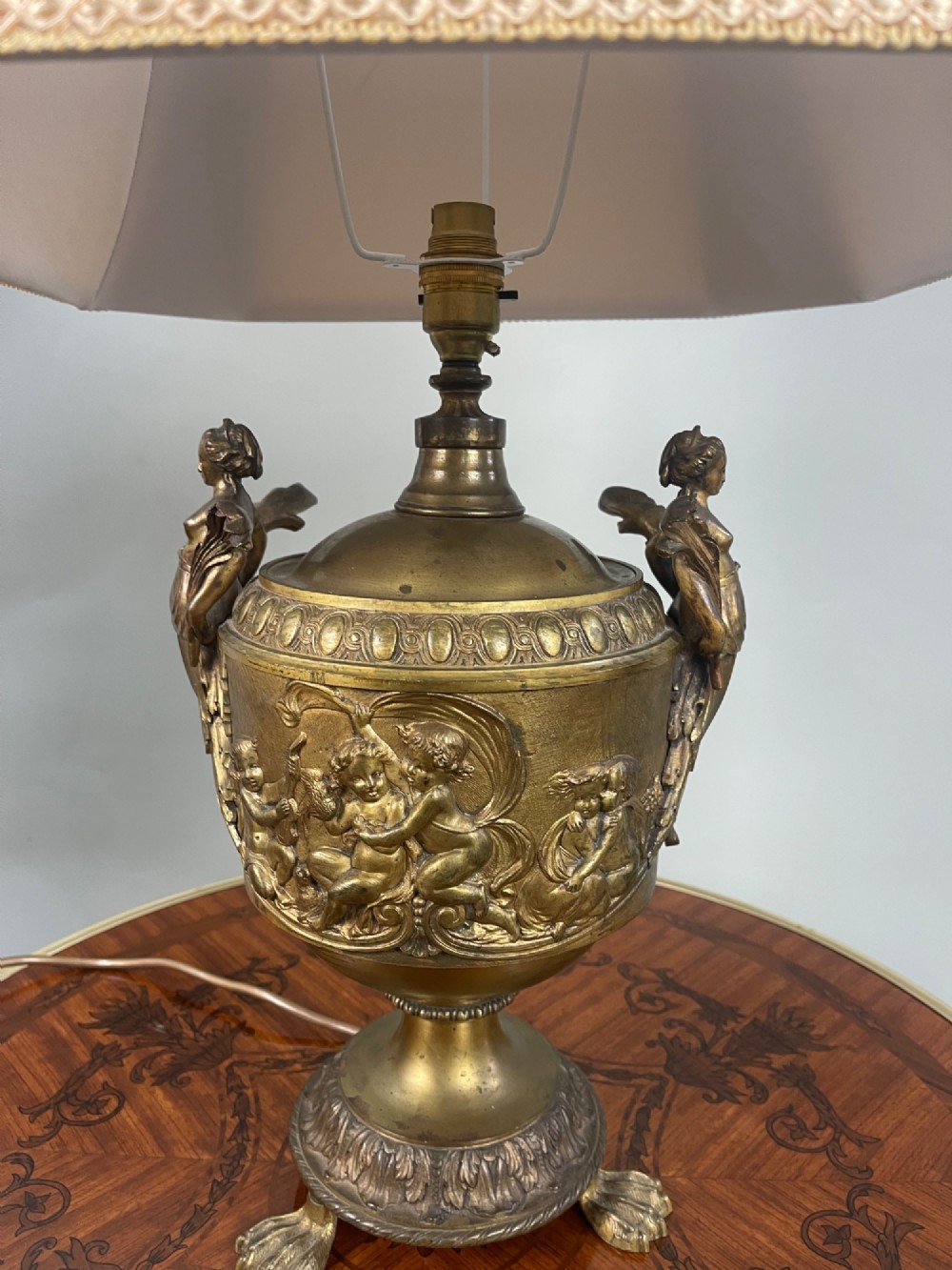 A pair of antique French gilt bronze urn-form table lamps decorated with putti reliefs and fitted with neutral fabric shades. View VI
