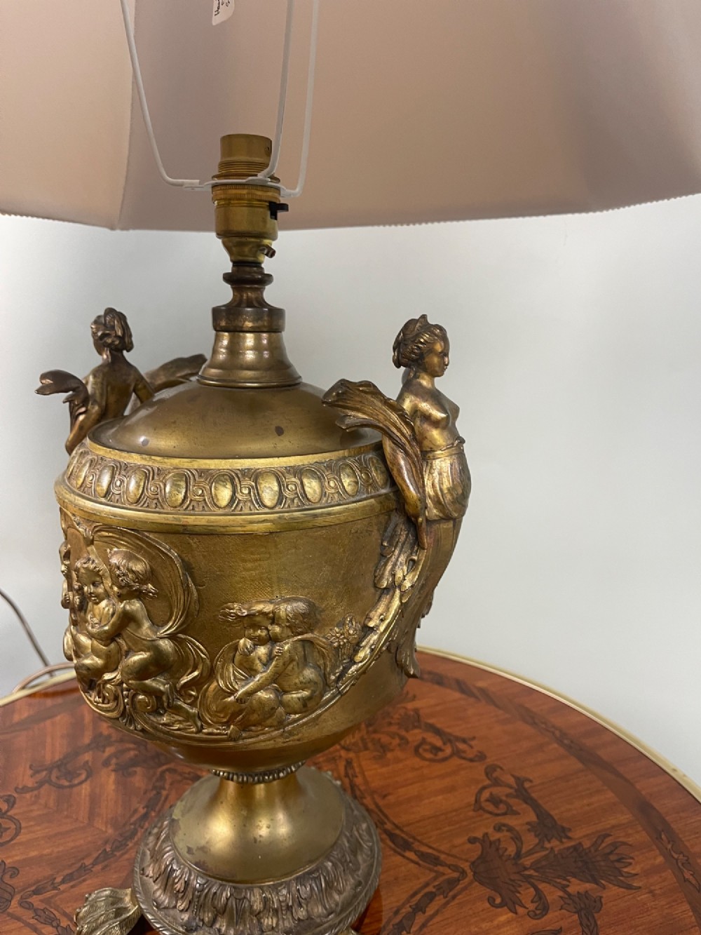 A pair of antique French gilt bronze urn-form table lamps decorated with putti reliefs and fitted with neutral fabric shades. View VII