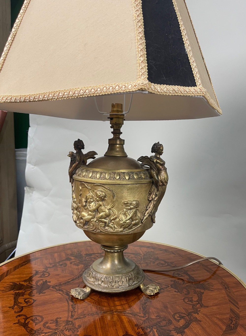 A pair of antique French gilt bronze urn-form table lamps decorated with putti reliefs and fitted with neutral fabric shades. View IX