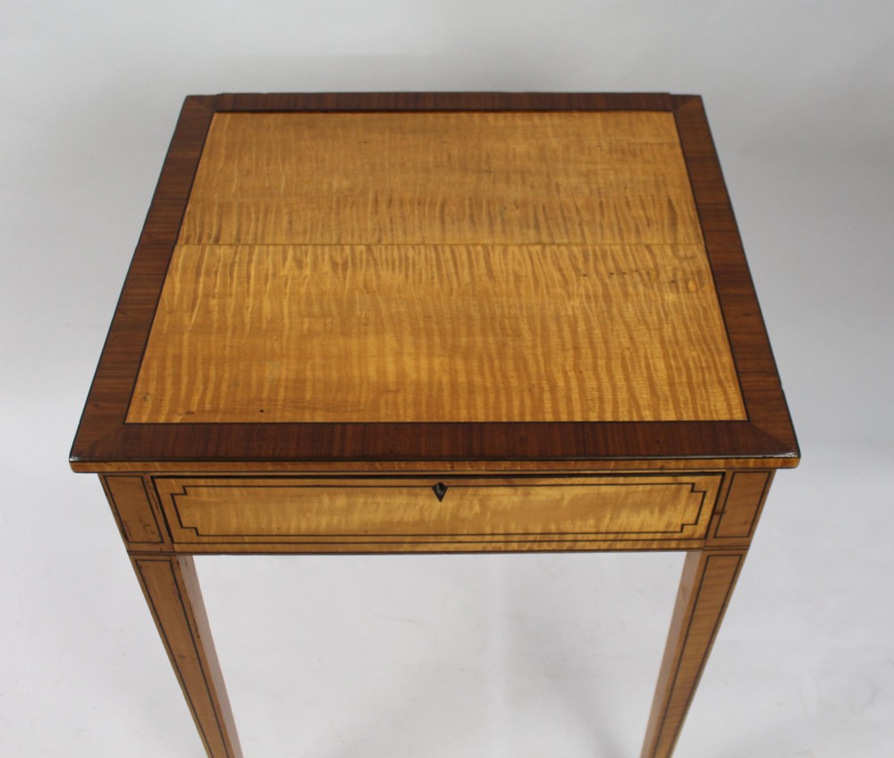 A George III Sheraton satinwood writing table featuring dark wood crossbanding, line inlay, a single drawer, square tapered legs, and brass castors. View VII