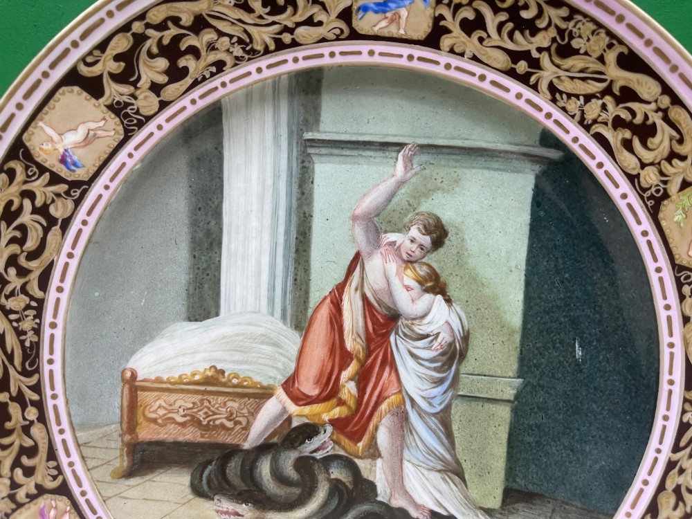 A circular 19th-century Meissen porcelain cabinet plate featuring a central hand-painted classical scene framed by a dark burgundy rim with intricate gilded scrollwork and cherub cartouches. View IV
