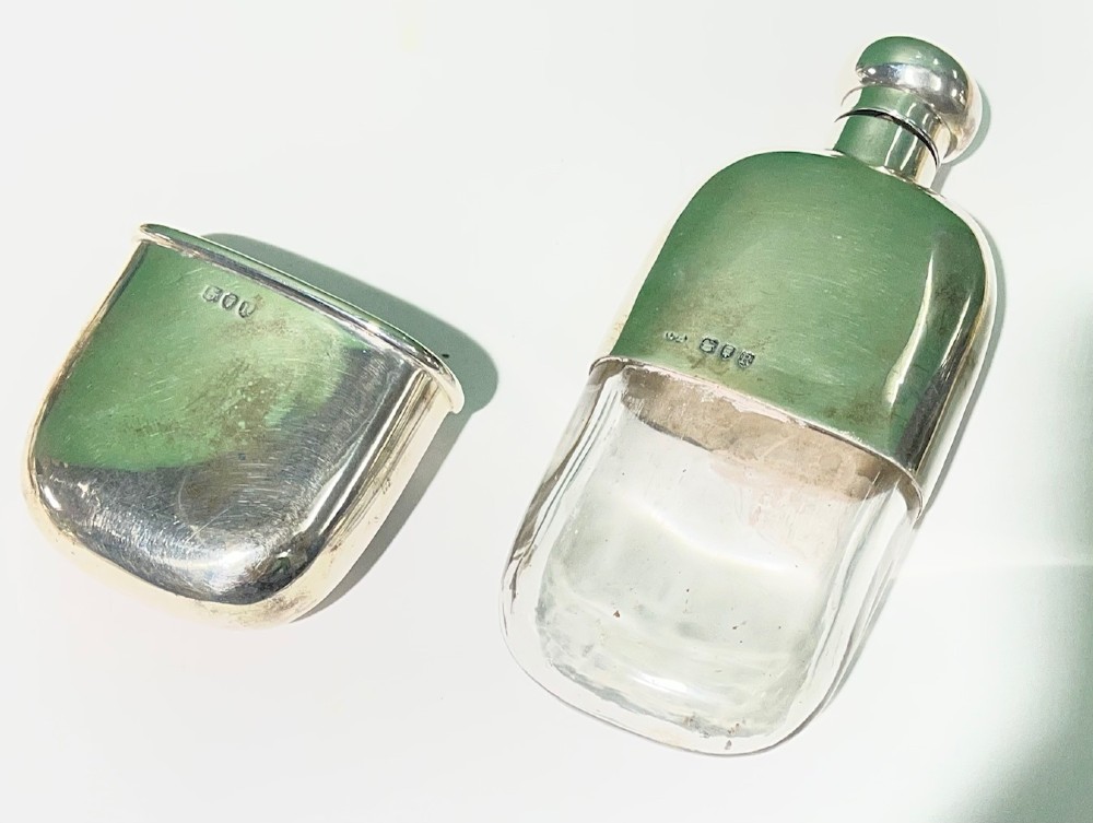 A late Victorian sterling silver spirit flask featuring a domed top and visible London hallmark stamps on the body. View V