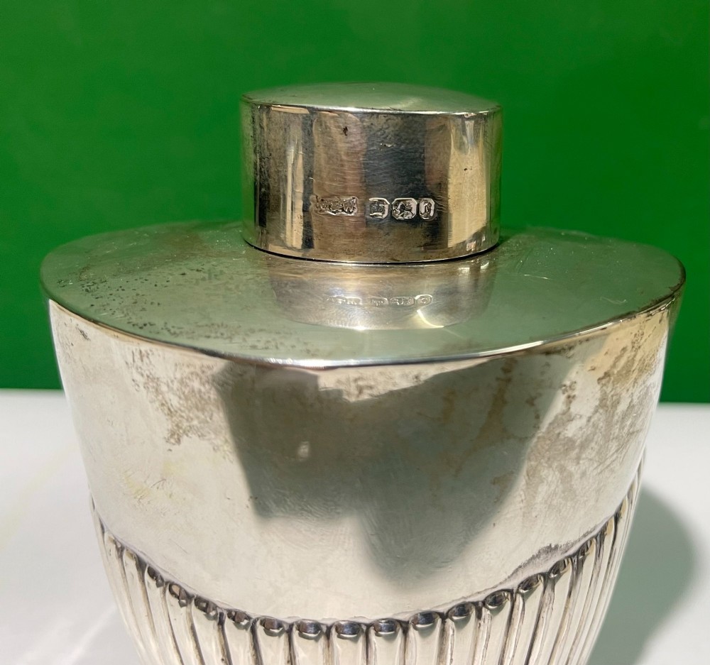 An Edwardian sterling silver jar featuring vertical fluted decoration around the lower body and official hallmarking stamped on the neck. View II