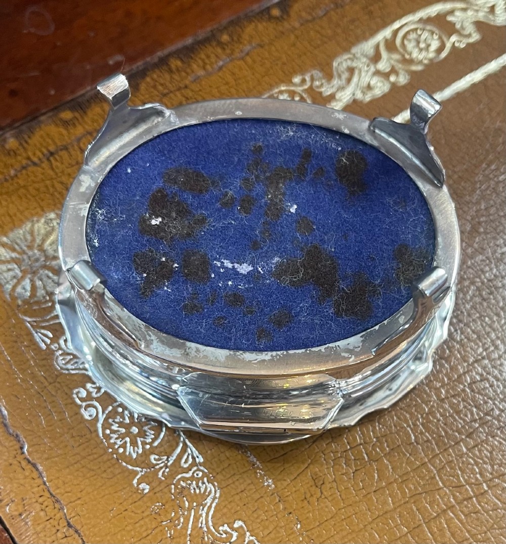 An oval sterling silver trinket box featuring an engine-turned wave pattern on the lid and resting on four small feet. View IV