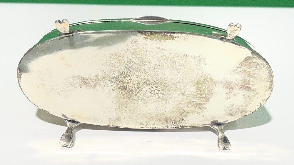 An oval sterling silver casket featuring a hinged lid, smooth polished exterior, raised cabriole feet, and visible British hallmarks. View III