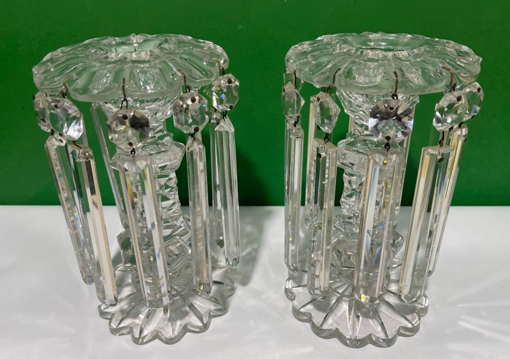 A pair of clear cut glass table lustres featuring faceted stems, starburst cut bases, and hanging crystal prism drops suspended from wire hooks. View II