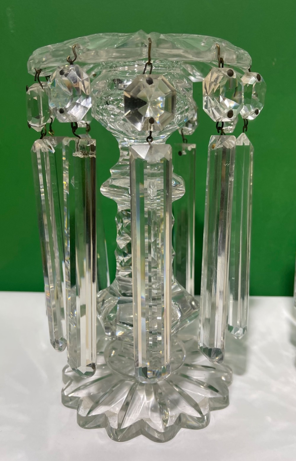 A pair of clear cut glass table lustres featuring faceted stems, starburst cut bases, and hanging crystal prism drops suspended from wire hooks. View III