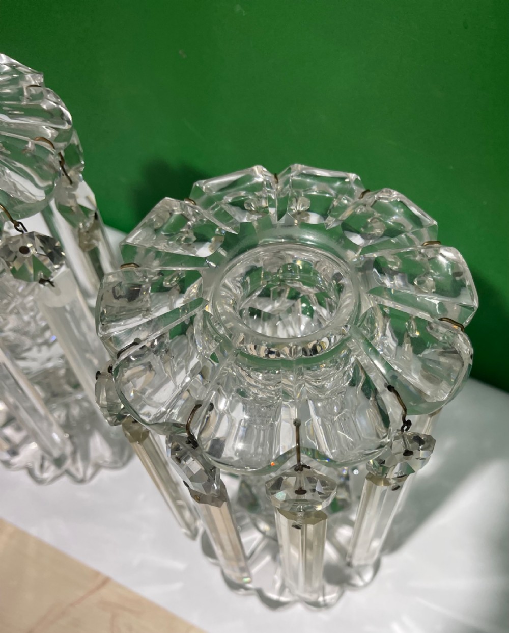 A pair of clear cut glass table lustres featuring faceted stems, starburst cut bases, and hanging crystal prism drops suspended from wire hooks. View V