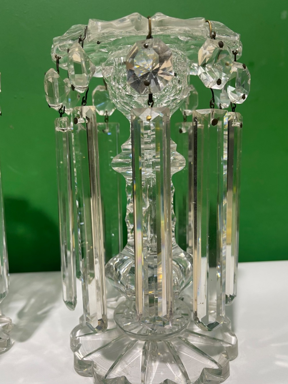 A pair of clear cut glass table lustres featuring faceted stems, starburst cut bases, and hanging crystal prism drops suspended from wire hooks. View VII