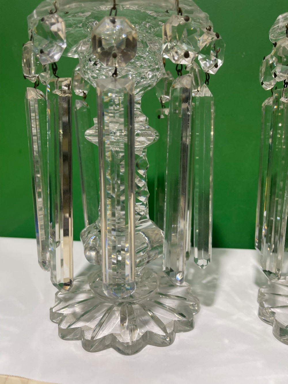 A pair of clear cut glass table lustres featuring faceted stems, starburst cut bases, and hanging crystal prism drops suspended from wire hooks. View VIII