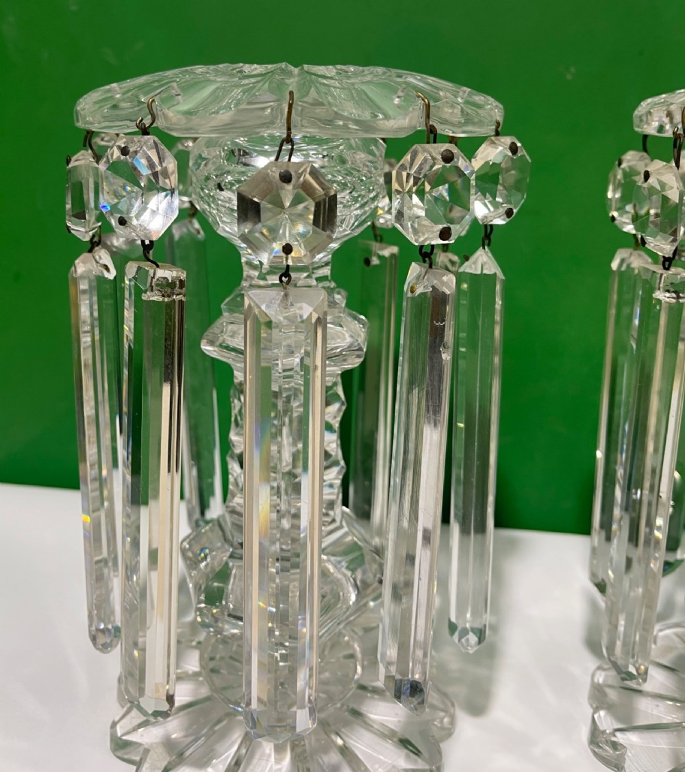 A pair of clear cut glass table lustres featuring faceted stems, starburst cut bases, and hanging crystal prism drops suspended from wire hooks. View IX