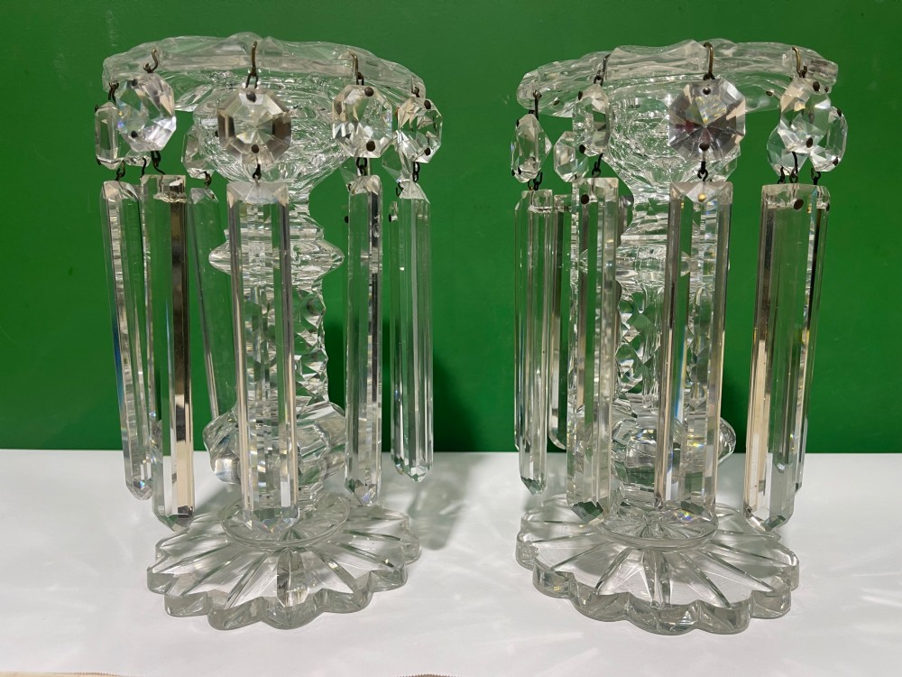 A pair of clear cut glass table lustres featuring faceted stems, starburst cut bases, and hanging crystal prism drops suspended from wire hooks. View XI
