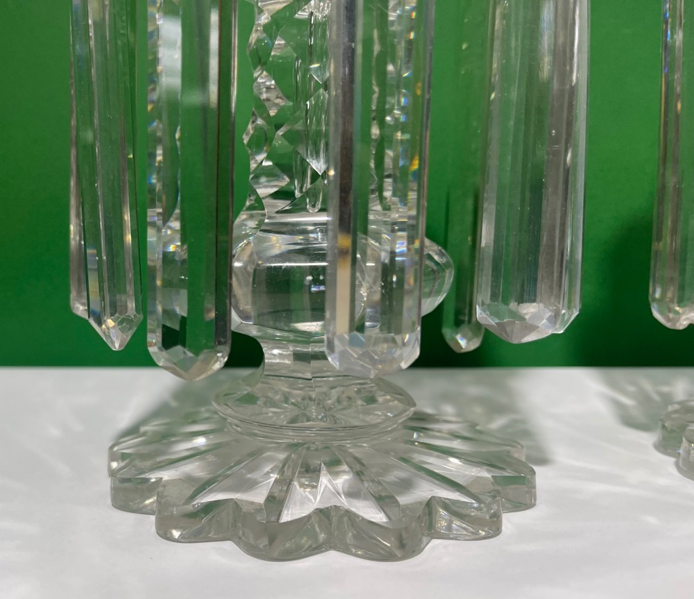 A pair of clear cut glass table lustres featuring faceted stems, starburst cut bases, and hanging crystal prism drops suspended from wire hooks. View XII