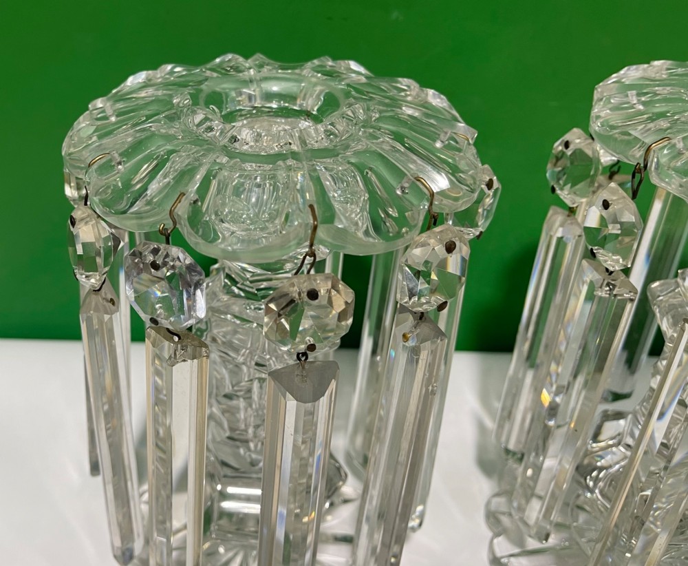 A pair of clear cut glass table lustres featuring faceted stems, starburst cut bases, and hanging crystal prism drops suspended from wire hooks. View XIII