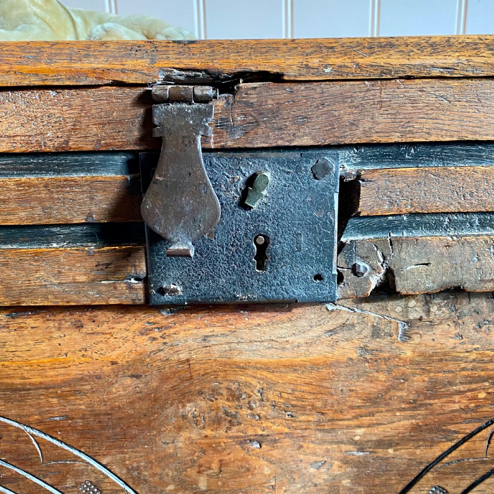 A 17th-century oak coffer displaying hand-carved lunette motifs across the front panel and an iron lockplate. View V