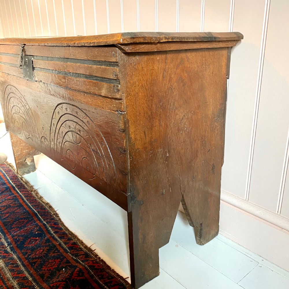 A 17th-century oak coffer displaying hand-carved lunette motifs across the front panel and an iron lockplate. View VI