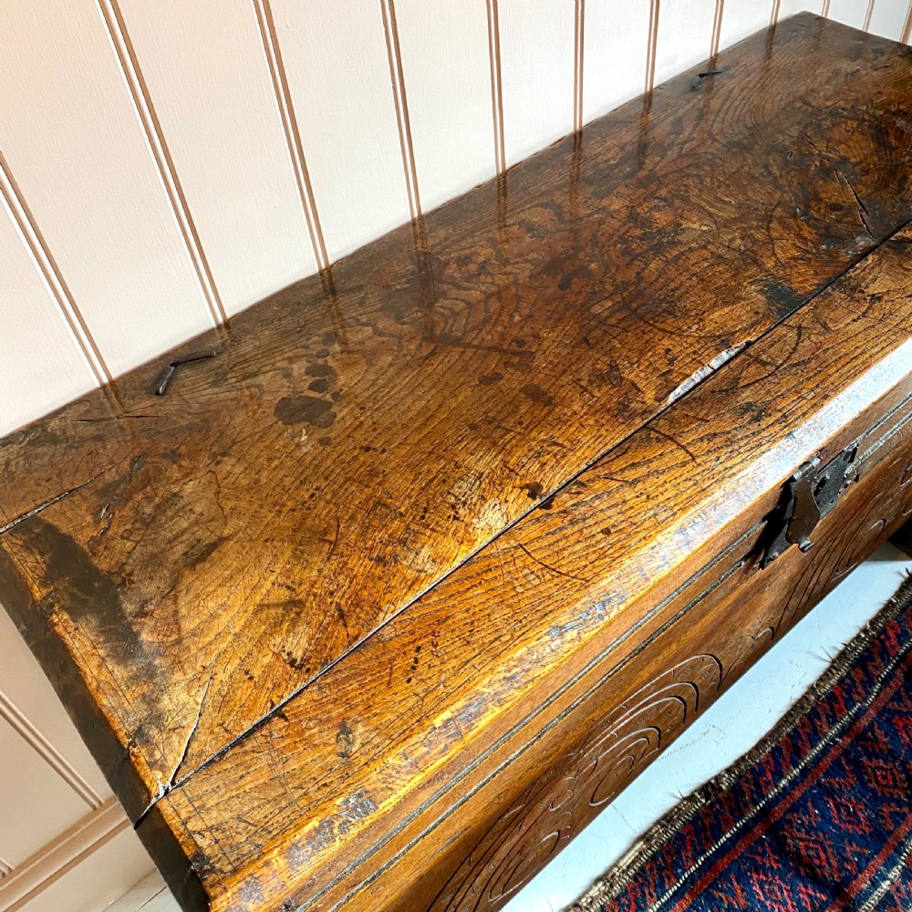 A 17th-century oak coffer displaying hand-carved lunette motifs across the front panel and an iron lockplate. View X