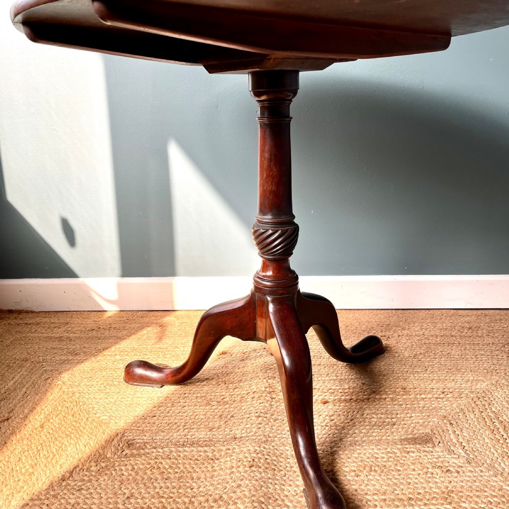 A Georgian mahogany tilt-top tripod table featuring a circular top, turned stem with a spiral carved knop, and three cabriole legs with pad feet. View IV