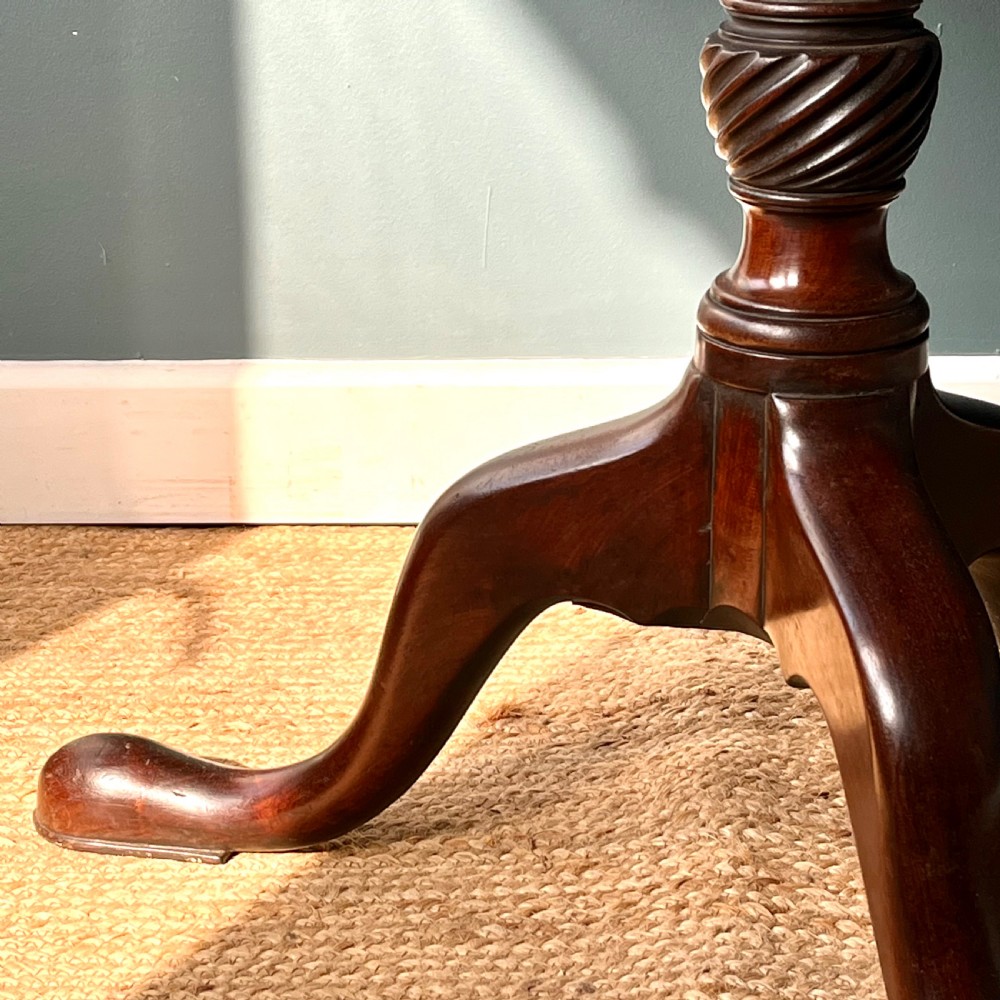 A Georgian mahogany tilt-top tripod table featuring a circular top, turned stem with a spiral carved knop, and three cabriole legs with pad feet. View V