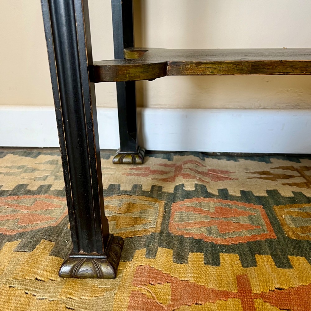 An ebonised Aesthetic Movement display cabinet featuring a glazed upper section with geometric glazing bars, hand-painted gilt motifs, a drawer, and slim legs with a bottom tier shelf. View VII