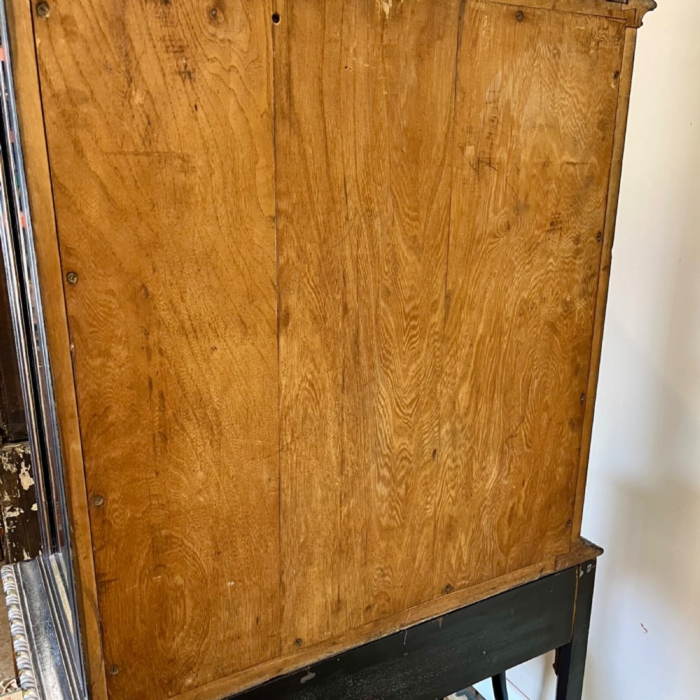 An ebonised Aesthetic Movement display cabinet featuring a glazed upper section with geometric glazing bars, hand-painted gilt motifs, a drawer, and slim legs with a bottom tier shelf. View XVII