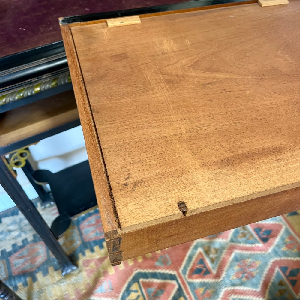 An ebonised Aesthetic Movement display cabinet featuring a glazed upper section with geometric glazing bars, hand-painted gilt motifs, a drawer, and slim legs with a bottom tier shelf. View XVIII