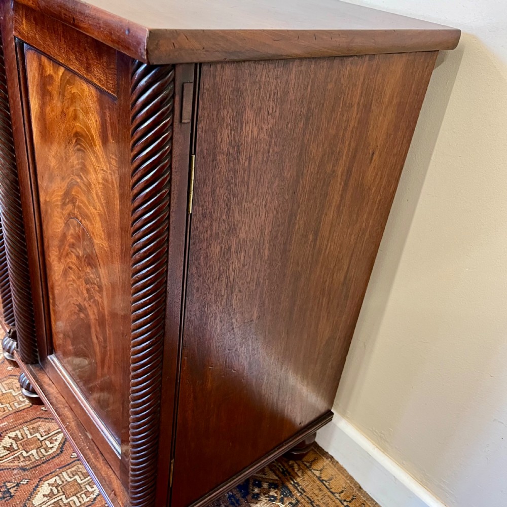 A pair of 19th-century mahogany bedside cupboards featuring flame mahogany panel doors, rope-twist carved side details, and turned feet. View VII