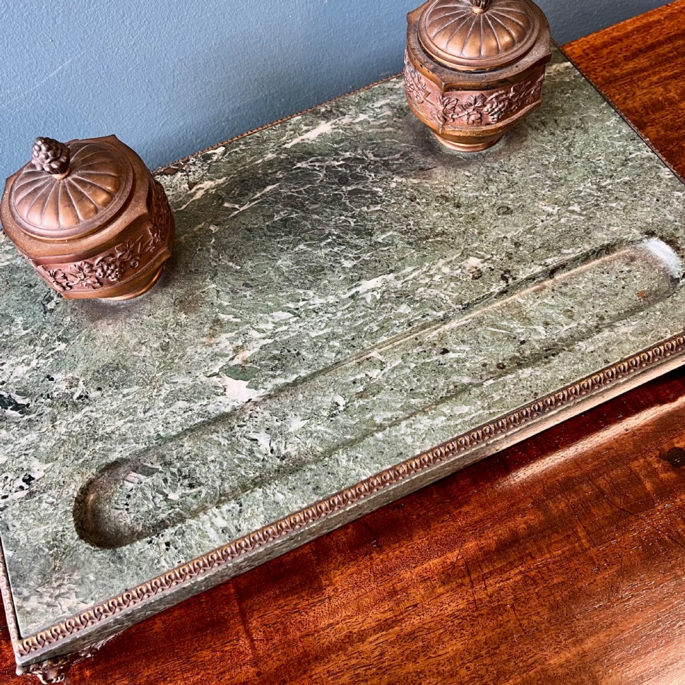 A French green marble desk set featuring a rectangular inkstand base with two raised gilt ormolu inkwells, a carved pen tray, ornate corner feet, and a matching marble rocking blotter. View X