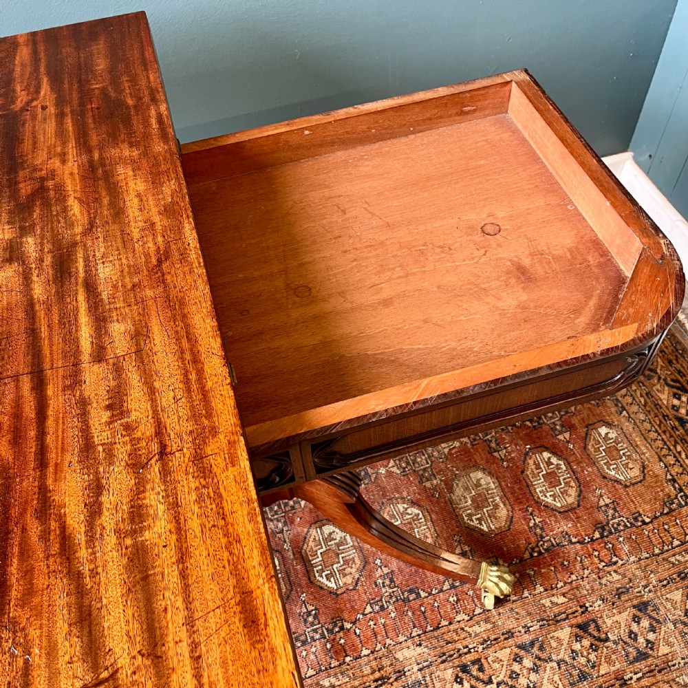 A 19th-century mahogany fold-over card table with a carved frieze, central pedestal, and splayed quadripartite legs ending in brass lion paw castors. View VIII