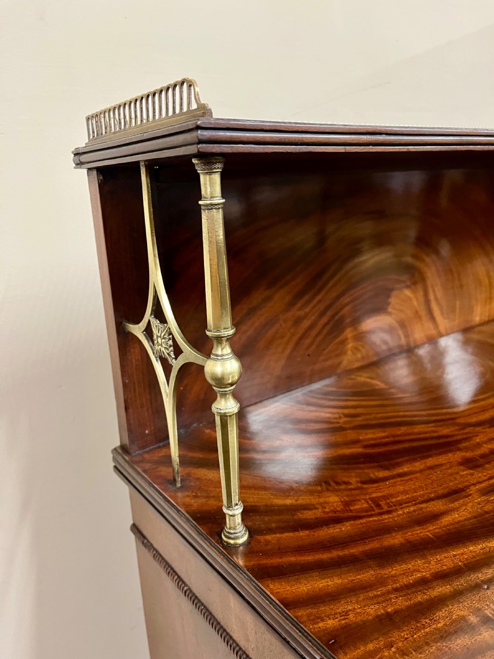 A 19th-century mahogany chiffonier featuring an upper shelf with a brass gallery, twin panelled cupboard doors flanked by turned side columns, resting on bun feet. View II